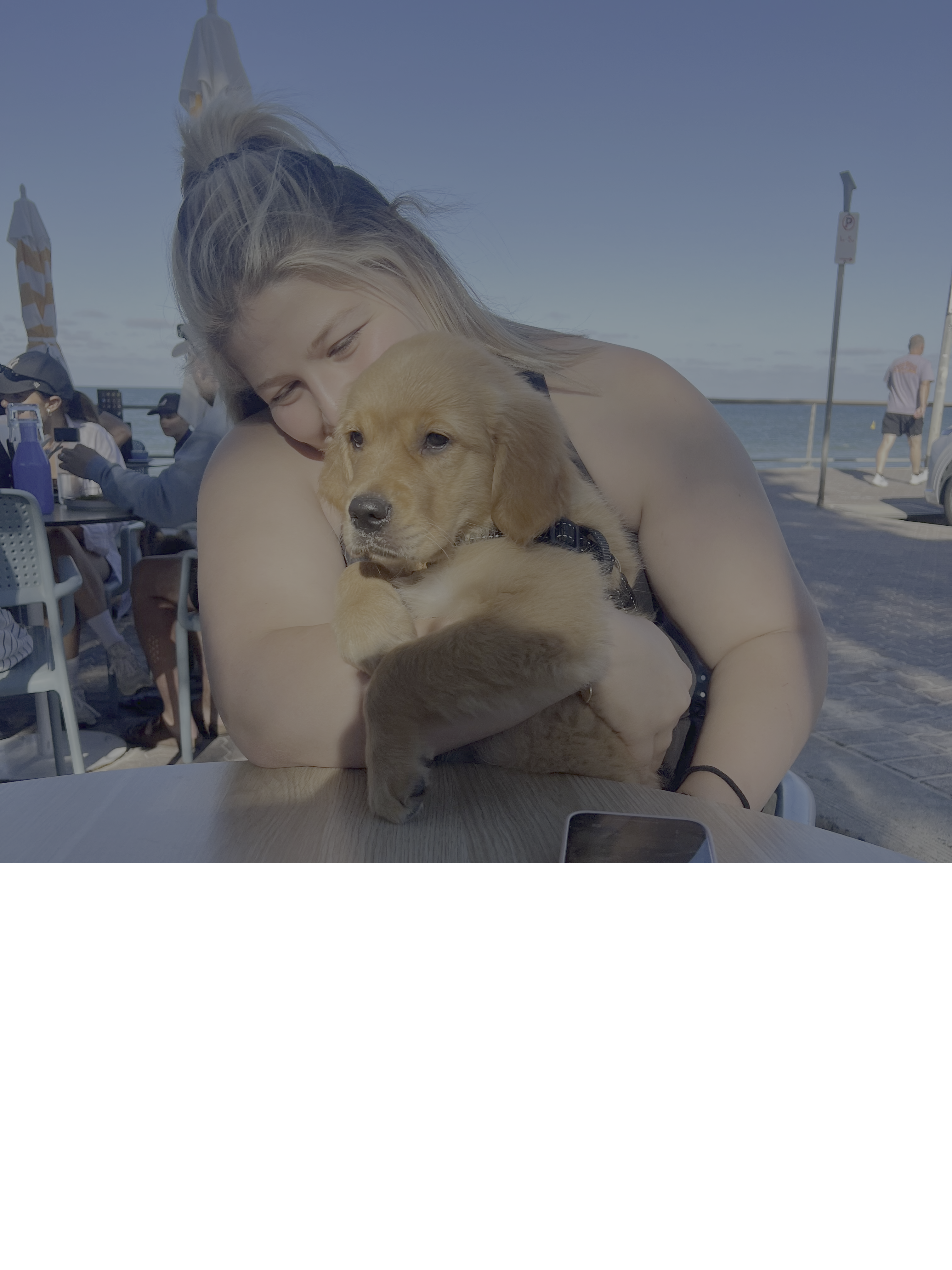 Ella holding a puppy by the beach
